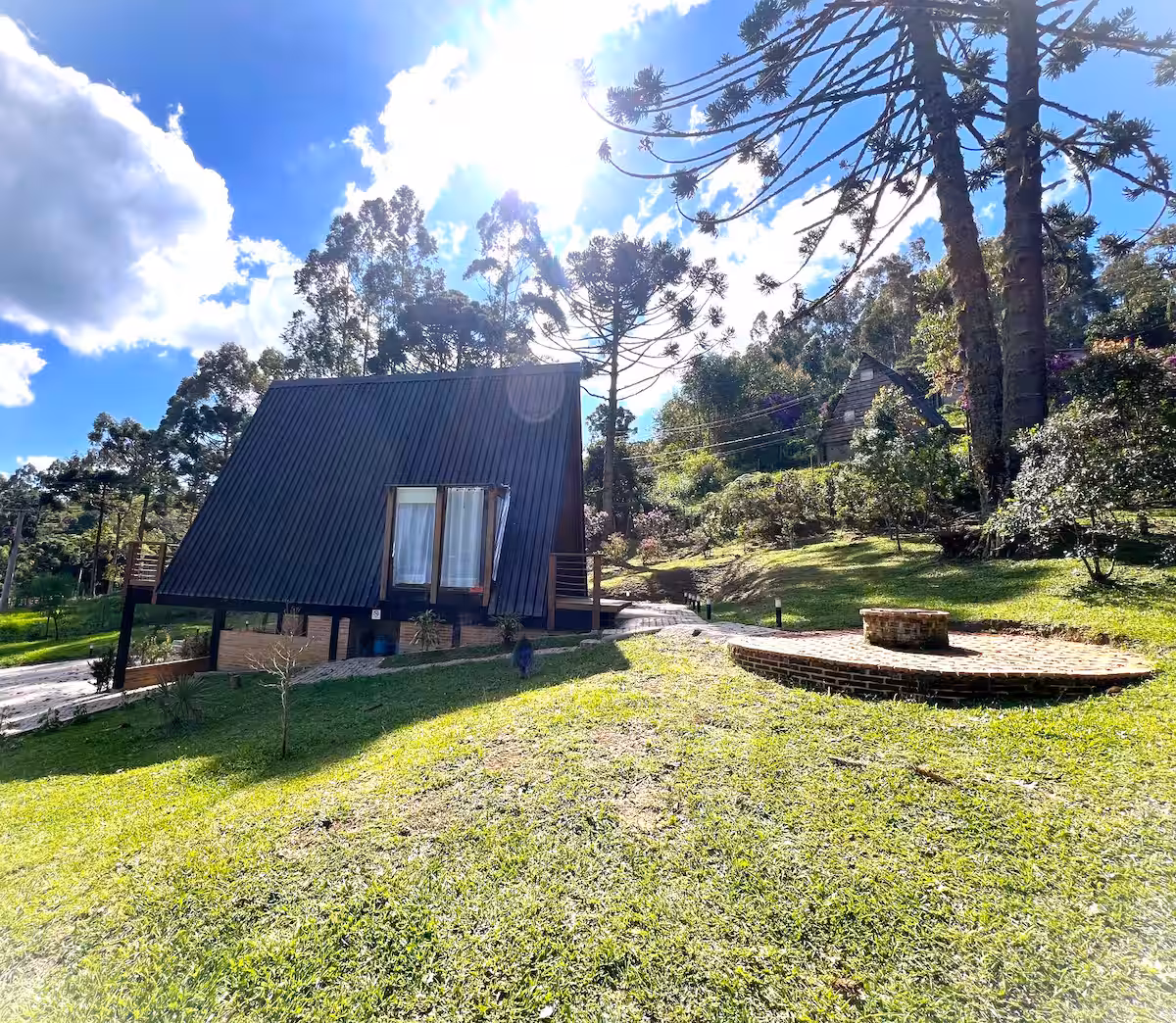 Cabana A-frame no jardim, com a luz do fim de tarde entre as árvores