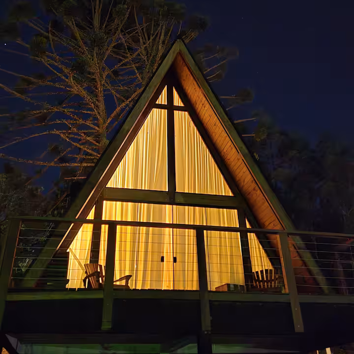 Cabana A-frame brilhando na noite estrelada da serra